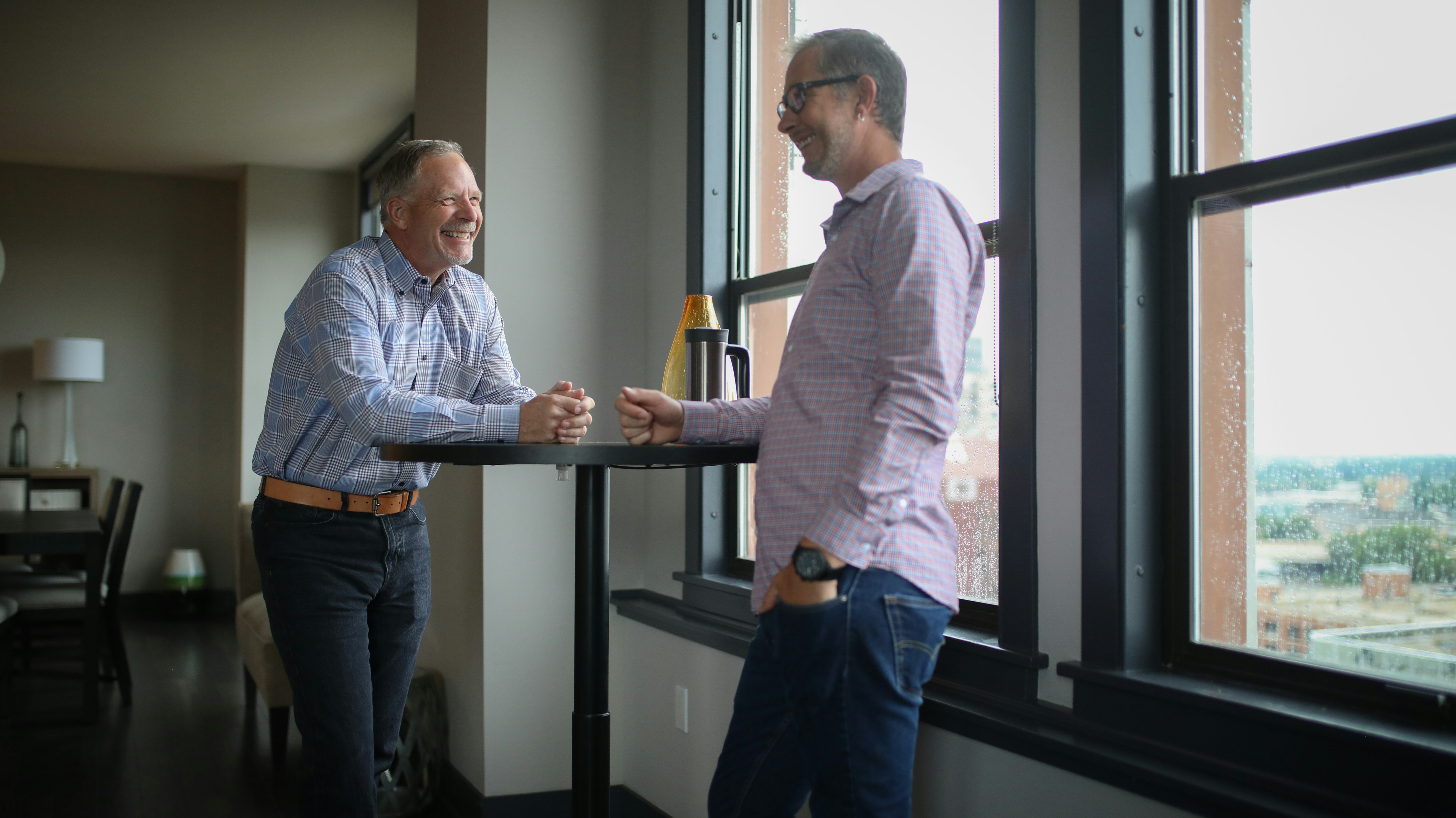 man in white dress shirt standing beside man in blue denim jeans